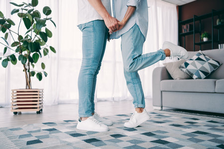 Couple holding hands in a cozy living room interior with bright natural light and warm detailingの写真素材