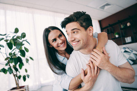 Loving Couple Embracing Joyfully in a Modern Living Room Highlighting Their Connection and Happiness at Home Togetherの写真素材