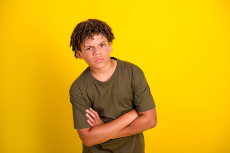 Funny creative pose a bold boy with crossed arms stands against a bright yellow background for bold stock photo vibesの写真素材