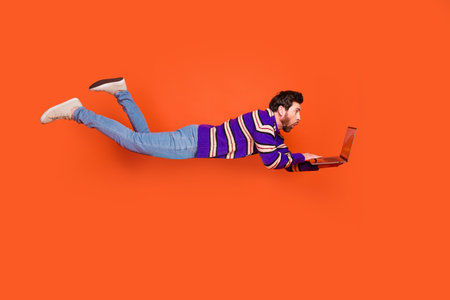 Full body photo of attractive young man amazed falling hold netbook dressed stylish striped purple...