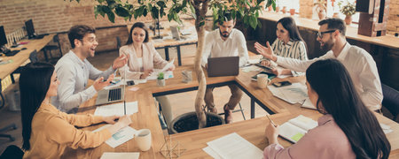 Photo of business men ladies people partners sitting around table desktop spacious big office seven members successful professionals good mood discussing new project indoorsの写真素材