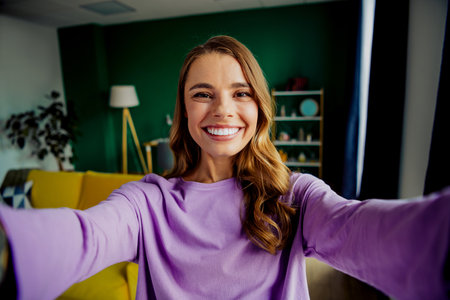 Smiling young woman enjoying a bright living room space, standing confidently in a modern interior, exuding joyful vibesの写真素材