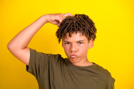 Playful boy with dreadlocks on a bright yellow background exudes casual fashion style and bold...