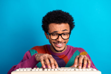 Young man with glasses typing enthusiastically on a keyboard with a cheerful smile and colorful...