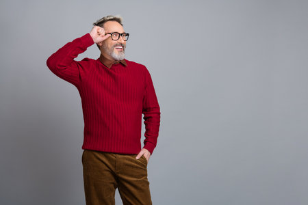 Handsome middle-aged businessman posing with style in casual office attire on a gray background, exuding success and charmの写真素材