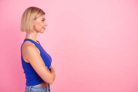 Profile portrait of nice young girl folded arms empty space wear blue top isolated on pink color backgroundの写真素材