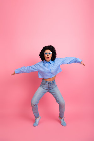 Young woman in casual fashion style with vibrant pink background exuding confidence and charm, posing with joyful energyの写真素材