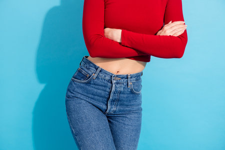Stylish young woman in casual attire posing confidently against blue background in fashionable red...