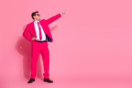 Young man in vibrant pink suit striking a dynamic pose against pink backgroundの写真素材