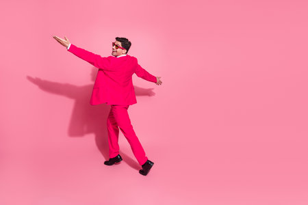 Charismatic man in a pink suit dancing cheerfully against a vibrant background, conveying joy, style, and modern eleganceの写真素材