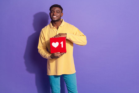 Photo portrait of attractive young man hold social media like icon dressed stylish yellow clothes...