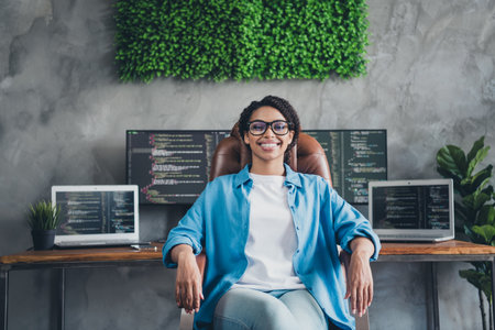 Photo of attractive young woman sit armchair confident boss wear blue shirt modern office programmer loft room interior indoors workspaceの写真素材