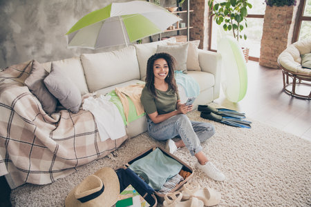 Photo of pretty cheerful lady wear casual t-shirt packing clothes summer vacation texting device indoors room home houseの写真素材