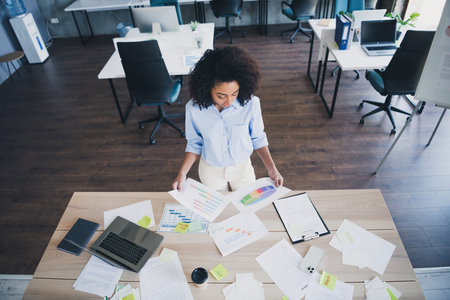 Top view photo of cheerful positive lady recruiter dressed shirt analyzing charts indoors workplace workstation loftの写真素材