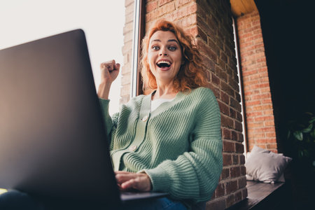 Photo of cheerful lady wear green cardigan winning game modern device indoors room home houseの写真素材