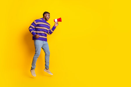 Full size photo of nice young man jump loudspeaker empty space isolated on yellow color backgroundの写真素材