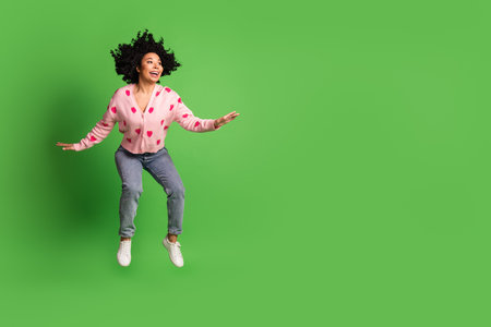 Full size photo of pretty young girl jumping look empty space wear strawberry print pink outfit isolated on green color backgroundの写真素材