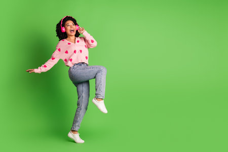 Full size photo of pretty young girl earphones dance have fun wear strawberry print pink outfit isolated on green color backgroundの写真素材