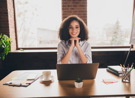 Successful businesswoman with curly hair working in a modern officeの写真素材