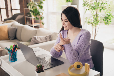 Photo of attractive young teen girl study netbook remotely video call dressed purple outfit bright cozy day light home interior living roomの写真素材