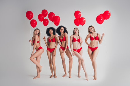 Full length photo of young ladies people hold air balloons dressed red lingerie white wall studio background no filter self acceptanceの写真素材