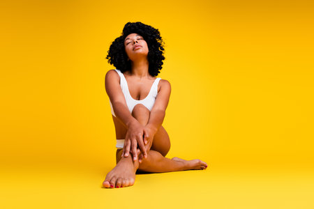 Studio no retouch photo of shiny dreamy lady dressed lingerie enjoying girls power blank space isolated yellow color backgroundの写真素材