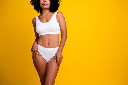 Studio no retouch cropped photo of adorable cheerful lady dressed lingerie loving herself copy space isolated yellow color backgroundの写真素材