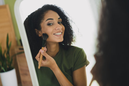 Photo of nice young girl apply powder brush wear green clothes modern daylight cozy interior flat indoorsの写真素材