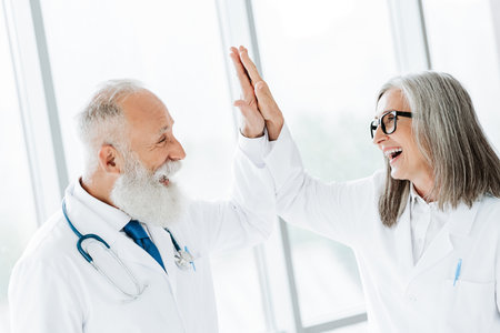 playful moment two doctors high five in bright clinic celebrating teamwork friendship and patient centered careの写真素材