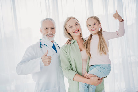 Playful family health care moment with doctor mother and daughter in a bright clinic smiling...