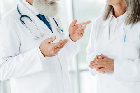 Playful professional doctors discuss patient care in clinic during a friendly medical consultation sceneの写真素材
