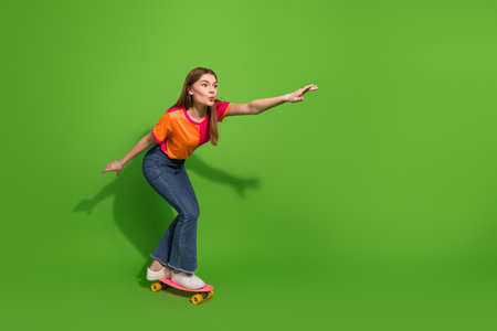 Young woman on skateboard posing with joyful energy against bright green background for lifestyle fashion and sports advertisingの写真素材