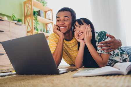 Photo of charming cute couple lying floor hugging homework together learning from home indoors flat apartmentの写真素材