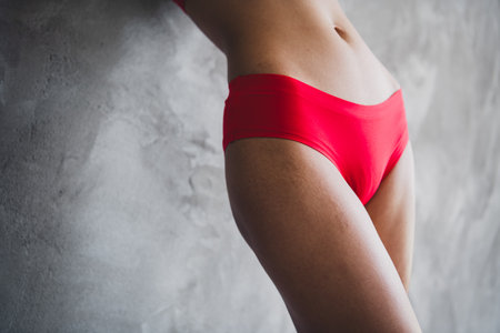 Photo of young lady perfect fit figure belly wear red lingerie concrete wall studio background no filter self acceptance all body perfectの写真素材