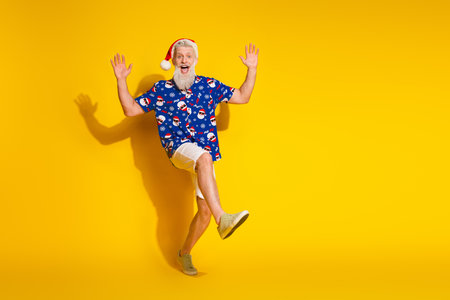 Full size photo of stylish modern santa dancing empty space wear xmas winter print shirt isolated on yellow color backgroundの写真素材
