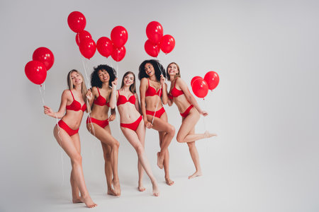 Full length photo of young ladies people pose hold air balloons dressed red lingerie white wall studio background no filter self acceptanceの写真素材