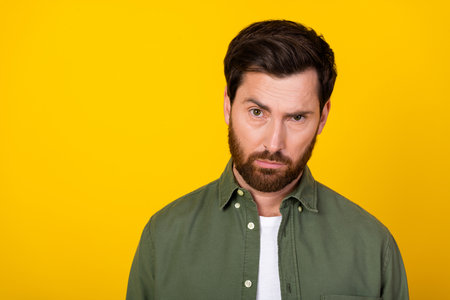 Portrait of nice young man raise eyebrow empty space wear khaki shirt isolated on yellow color backgroundの写真素材