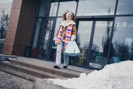 Full body portrait of nice young girl hold shop bags outerwear walk snowy weather mall street outdoors