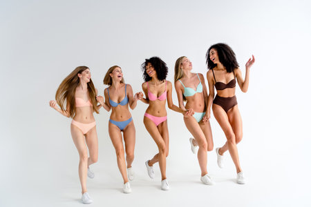Full body photo no filter of young girls posing body positive run hold hands wear colorful lingerie natural day light studio backgroundの写真素材