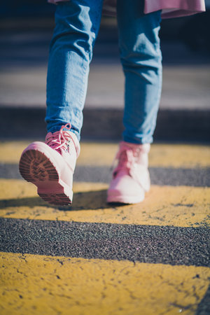 Cropped vertical photo of young girl pink boots walk pedestrian crossing street outdoorsの写真素材