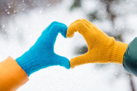 Photo of two hands wear gloves yellow blue show gesture sign heart symbol love romantic feelings...