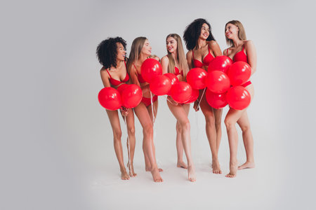 Full length photo of young ladies people hold air balloons dressed red lingerie white wall studio background no filter self acceptanceの写真素材