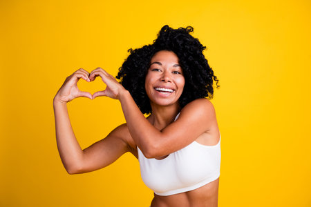 Studio no retouch photo of stunning sensual lady dressed lingerie loving body positive showing hands heart isolated yellow color backgroundの写真素材