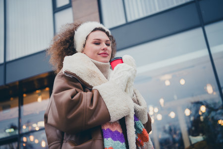 Portrait of nice young girl closed eyes smell coffee wear jacket walk snowy weather city street outdoorsの写真素材