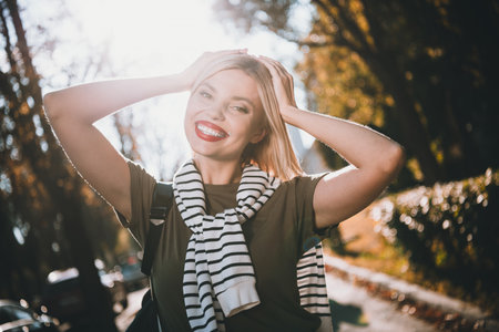 Photo of pretty young blonde woman touch head posing wear khaki clothes tied shoulders sweater walk...