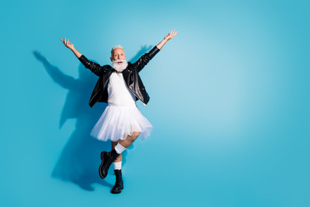 Photo of happy senior man dancing ballet raise hands wear female outfit isolated blue color backgroundの写真素材