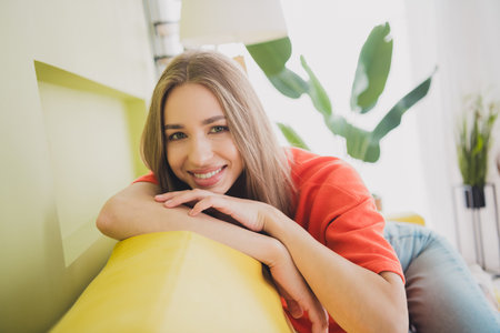 Photo of nice young girl sit sofa dreamy wear orange clothes enjoy modern bright cozy spring interior flat indoorsの写真素材