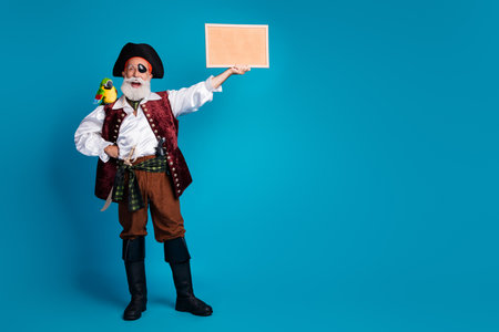 Full size photo of old funny pirate male hold picture frame dressed carnival party costume party isolated blue color backgroundの写真素材