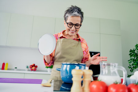 Charming senior woman enjoying her time in the kitchen preparing a delicious homemade meal with fresh ingredients and flairの写真素材
