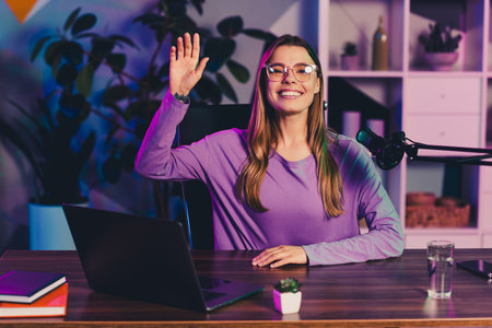 Content creator streaming from a home office with modern equipment in the evening under vibrant neon...